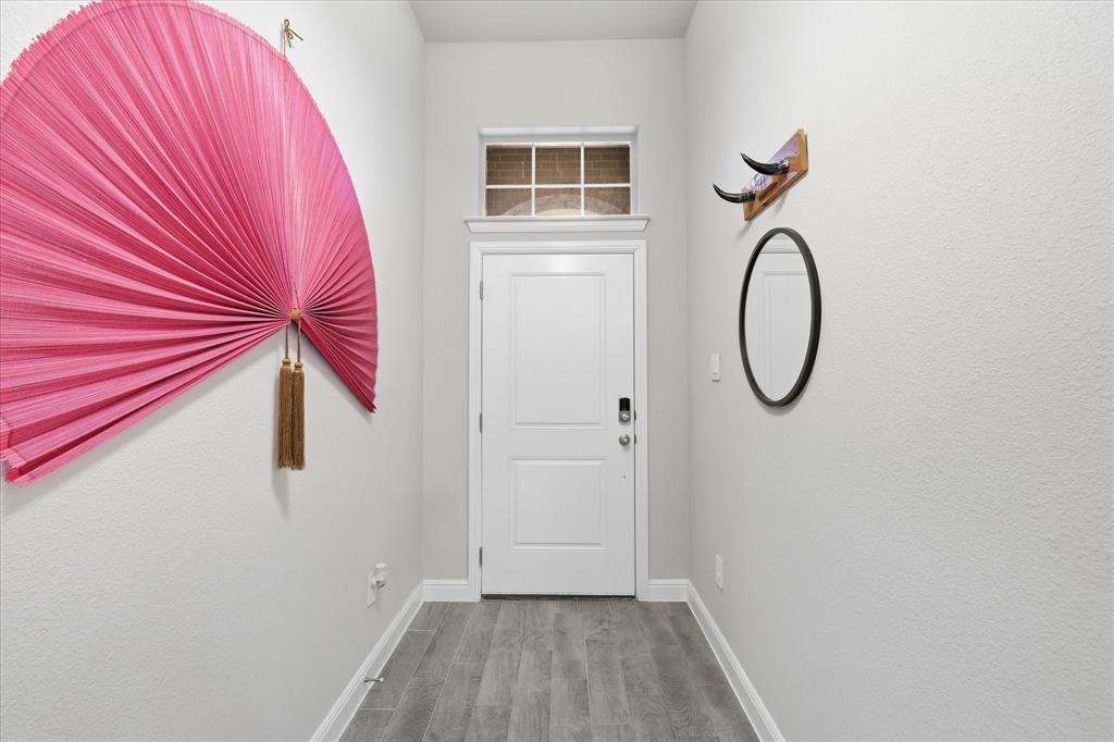 Entryway featuring a paneled door with a transom window, wood-finish flooring, and crisp white trim