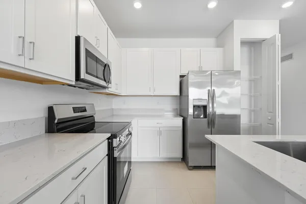 a kitchen with stainless steel appliances granite countertop a refrigerator a stove and a sink