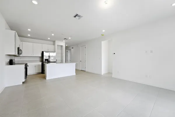 a view of kitchen with kitchen island white cabinets and refrigerator
