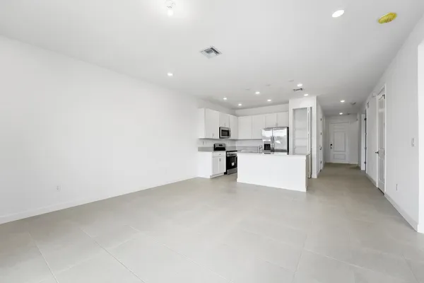 a view of kitchen with refrigerator and white cabinets