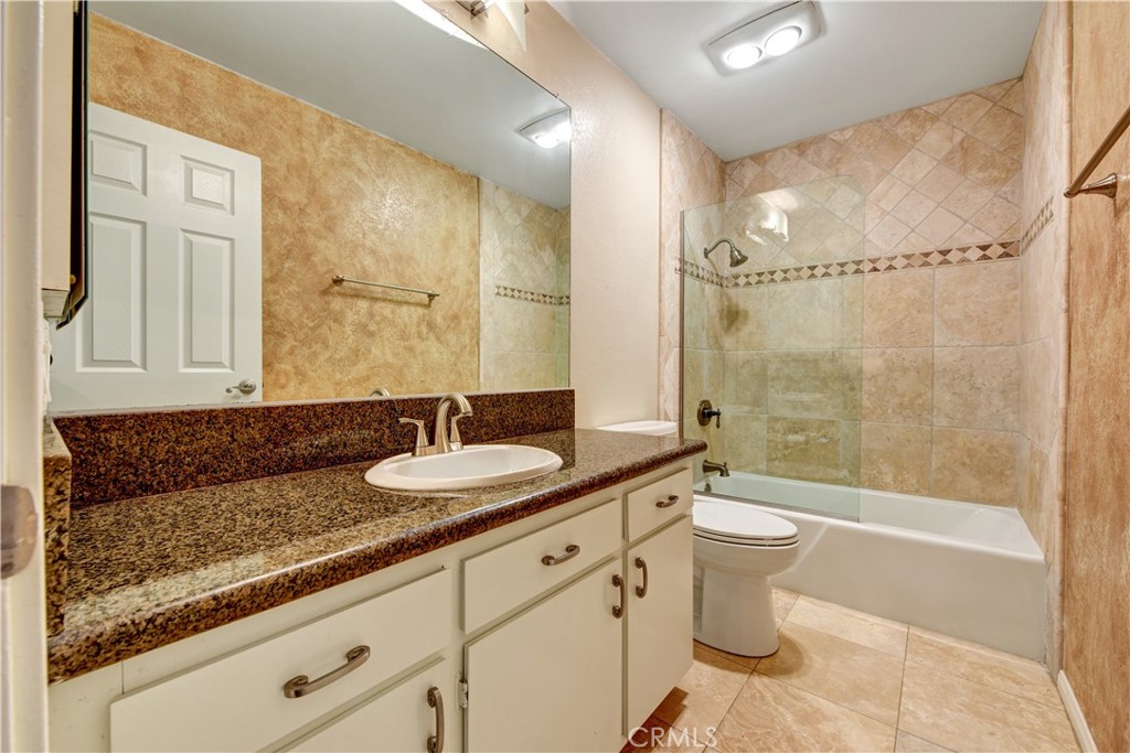 6316 Marina Pacifica Drive North Long Beach, CA 90803 - Photo 12 of 21 a bathroom with a granite countertop sink a toilet a mirror and shower