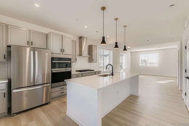 a large kitchen with stainless steel appliances a refrigerator a sink and wooden floors