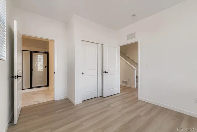a view of an empty room with wooden floor and closet
