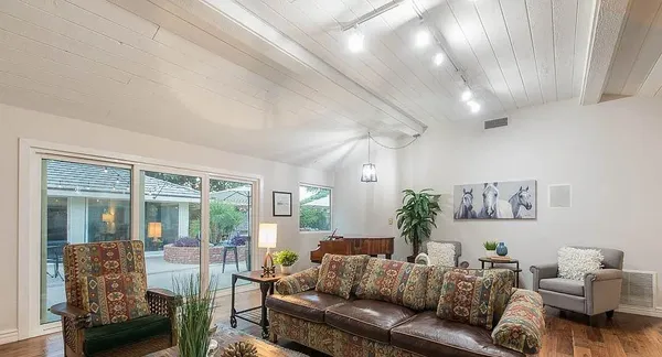 a kitchen with stainless steel appliances granite countertop a refrigerator a sink dishwasher a stove and a dining table with wooden floor