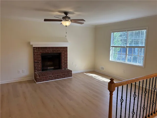 a view of an empty room with wooden floor and a fireplace