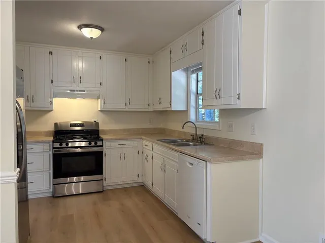 a kitchen with granite countertop white cabinets and stainless steel appliances