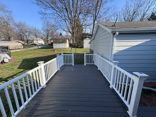a view of a house with wooden deck next to a yard