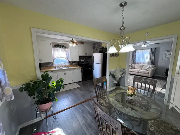 a dining room with wooden floor a chandelier a wooden table and chairs