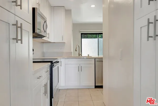 a kitchen with cabinets stainless steel appliances granite countertop white cabinets a microwave a sink and a counter space