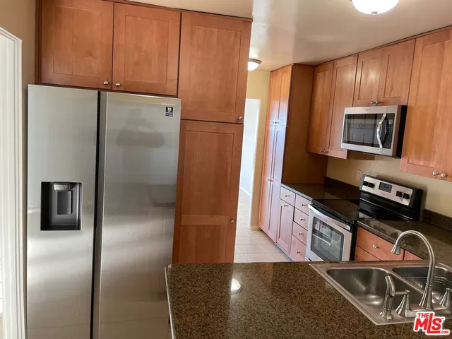 a kitchen with stainless steel appliances granite countertop a refrigerator a stove and a sink with wooden floor