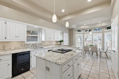 a kitchen with granite countertop sink stove and white cabinets with wooden floor