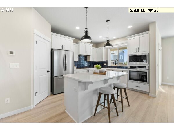 223 North 89th Loop, Unit 80 Ridgefield, WA 98642 - Photo 5 of 32 a kitchen with stainless steel appliances kitchen island granite countertop a refrigerator a microwave oven a sink with island and chairs