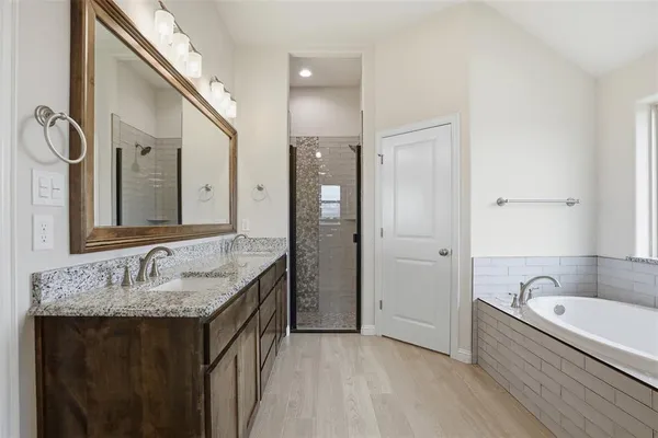 a bathroom with a granite countertop tub sink and mirror