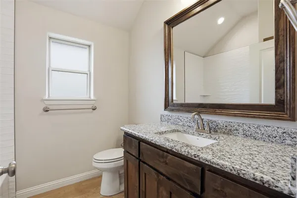 a bathroom with a granite countertop sink a toilet and a mirror
