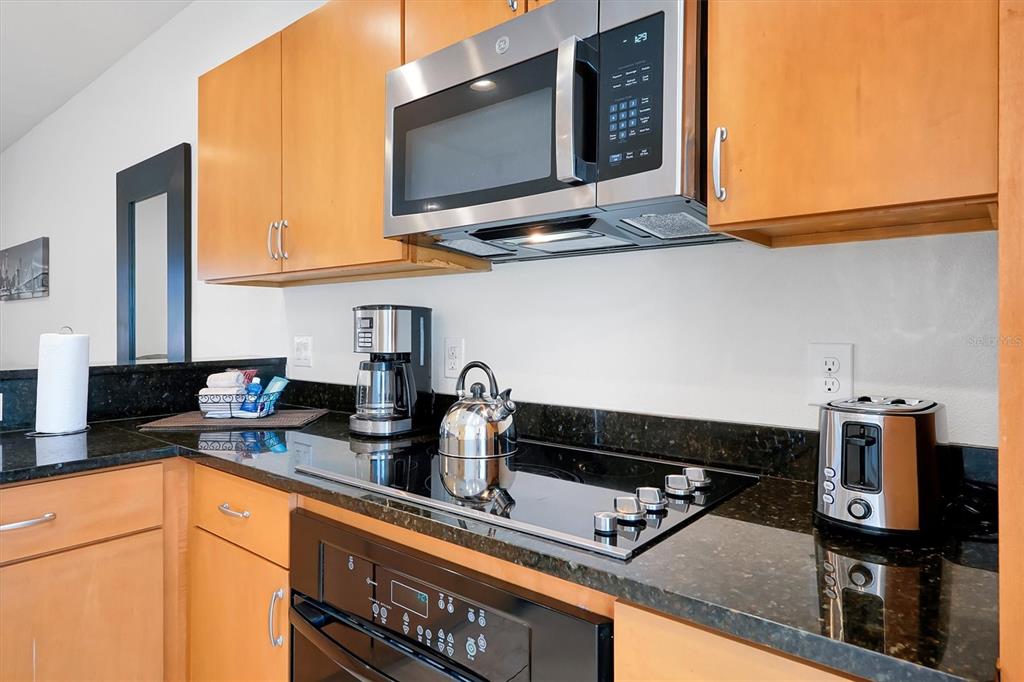 3011 Red Ginger Road Kissimmee, FL 34747 - Photo 11 of 62 a kitchen with stainless steel appliances granite countertop a sink dishwasher a stove a microwave oven and a dining table with wooden cabinet