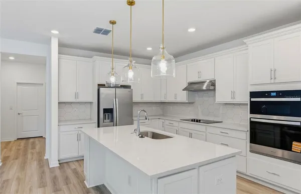 a kitchen with a sink a stove a refrigerator and cabinets