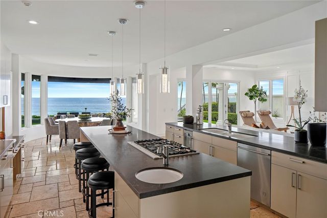 a kitchen with stainless steel appliances granite countertop a sink a stove and chairs