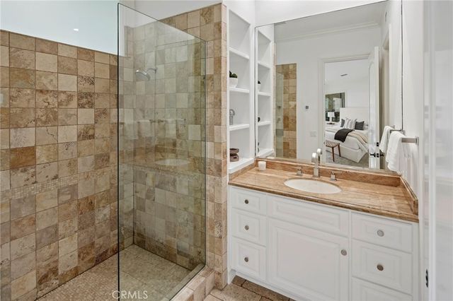 a bathroom with a granite countertop sink a mirror a glass door shower