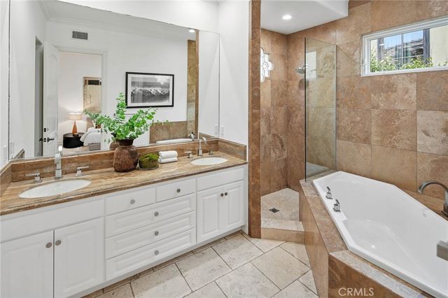 a spacious en suite bathroom with a granite countertop tub sink and mirror