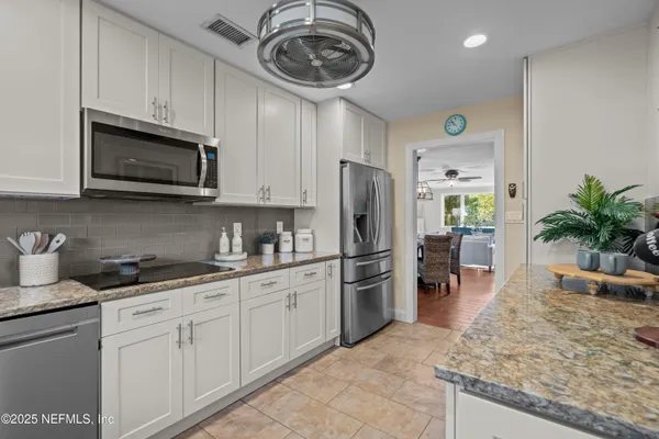 a kitchen with stainless steel appliances granite countertop a refrigerator a stove a sink a oven with a dining table and chairs