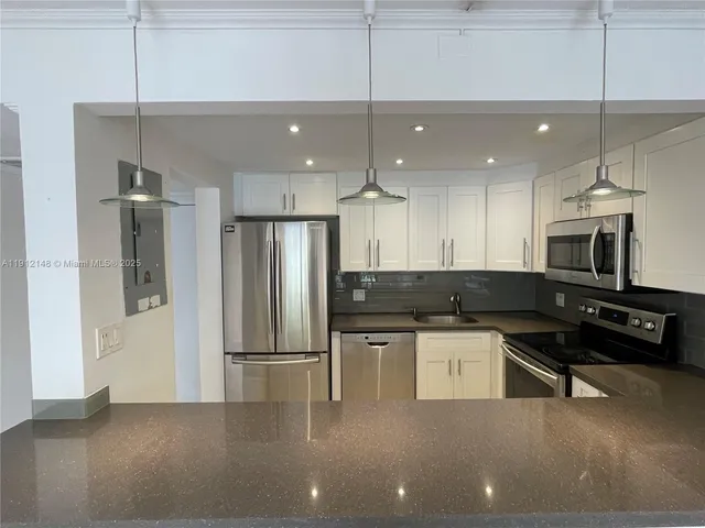 a kitchen with stainless steel appliances kitchen island a refrigerator and a stove top oven