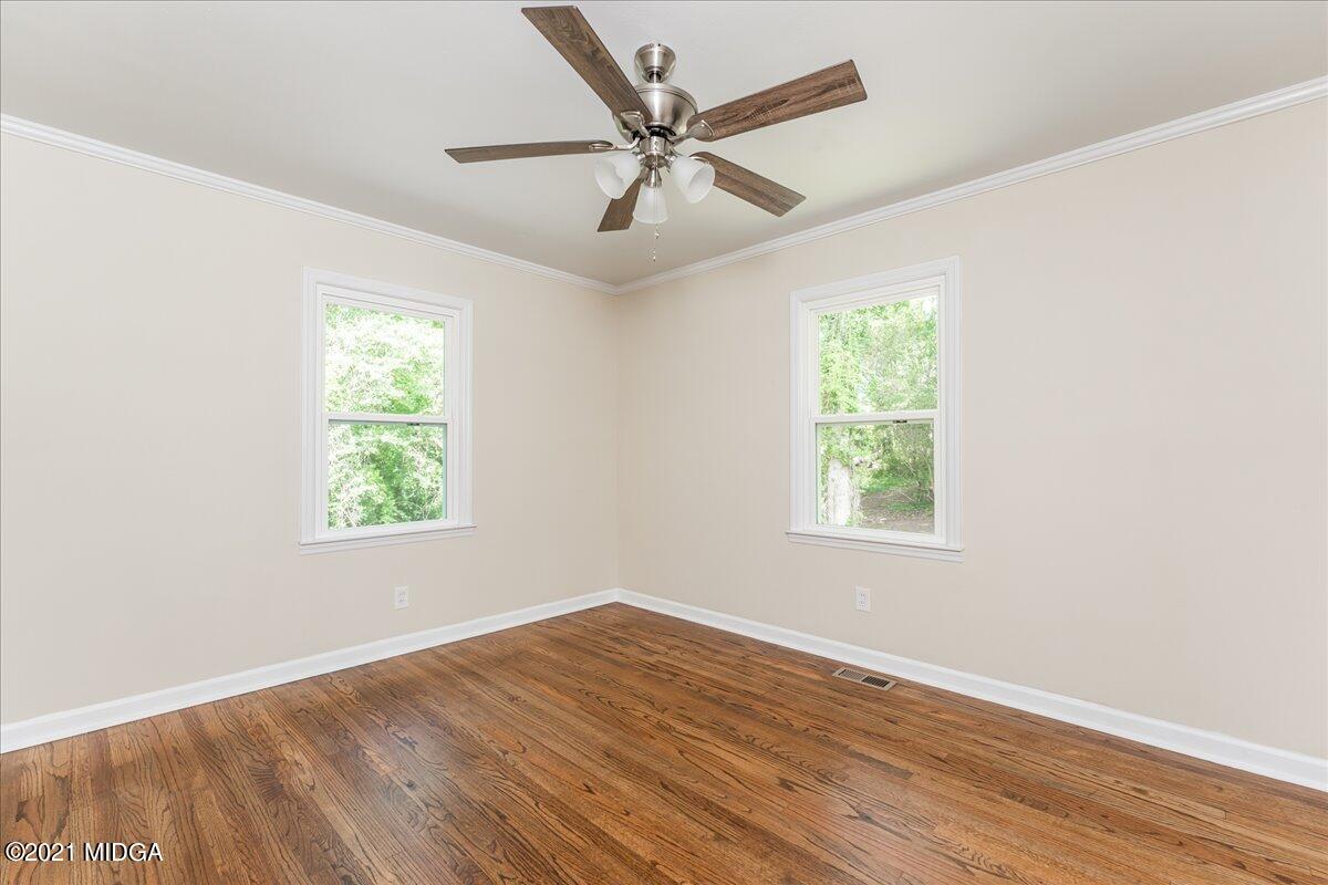 5611 Sardis Church Road Macon, GA 31216 - Photo 12 of 32 an empty room with wooden floor chandelier fan and windows