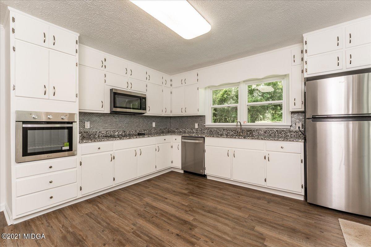 5611 Sardis Church Road Macon, GA 31216 - Photo 6 of 32 a kitchen with granite countertop white cabinets and white appliances