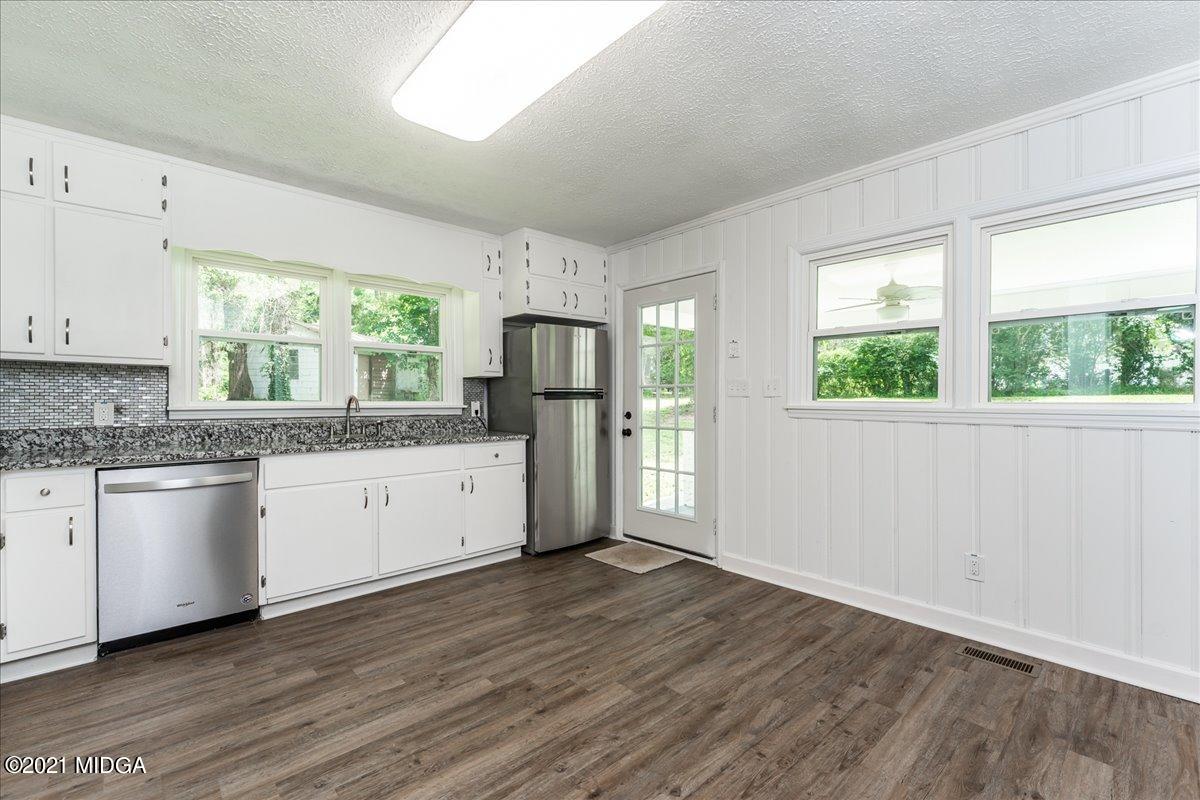 5611 Sardis Church Road Macon, GA 31216 - Photo 7 of 32 a kitchen with a wooden floor a window cabinets and stainless steel appliances