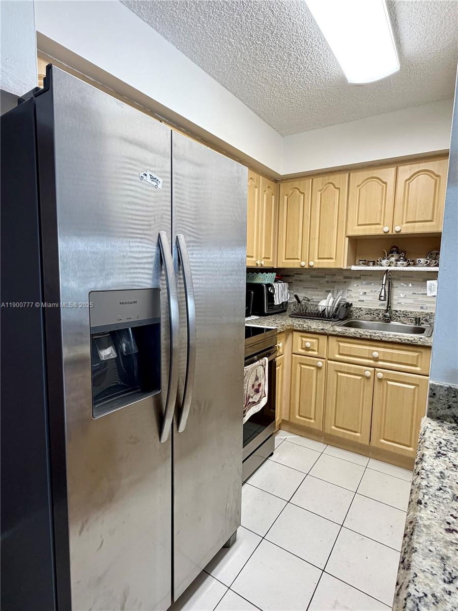 5201 Northwest 7th Street, Unit 212 Miami, FL 33126 - Photo 29 of 34 a kitchen with granite countertop a refrigerator and a sink