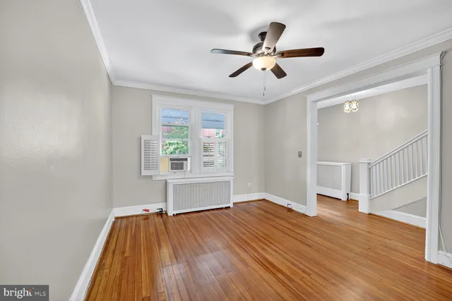 a view of empty room with wooden floor and fan