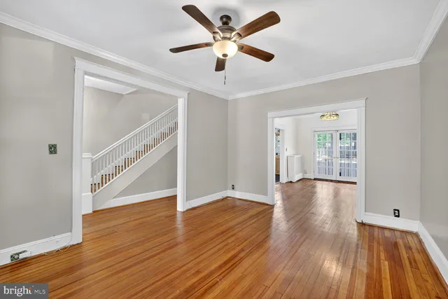 a view of an empty room with wooden floor and a ceiling fan
