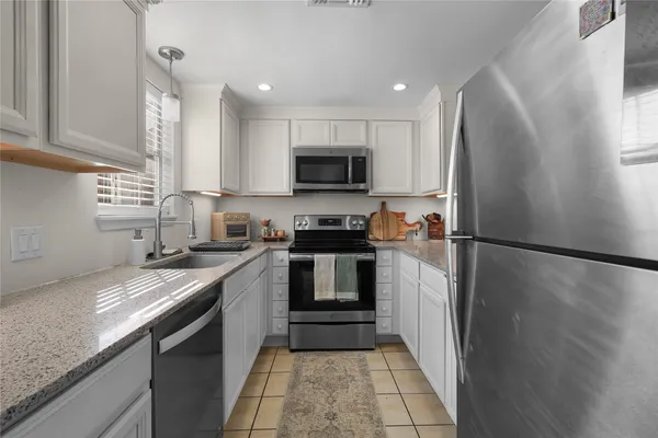 a kitchen with granite countertop a sink stainless steel appliances and cabinets