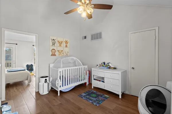 a view of a bedroom with wooden floor and a ceiling fan