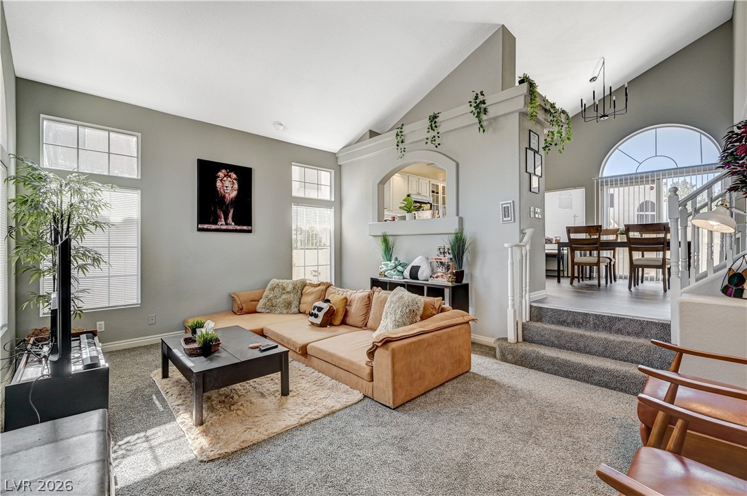 Carpeted living room with lofted ceiling and stairs