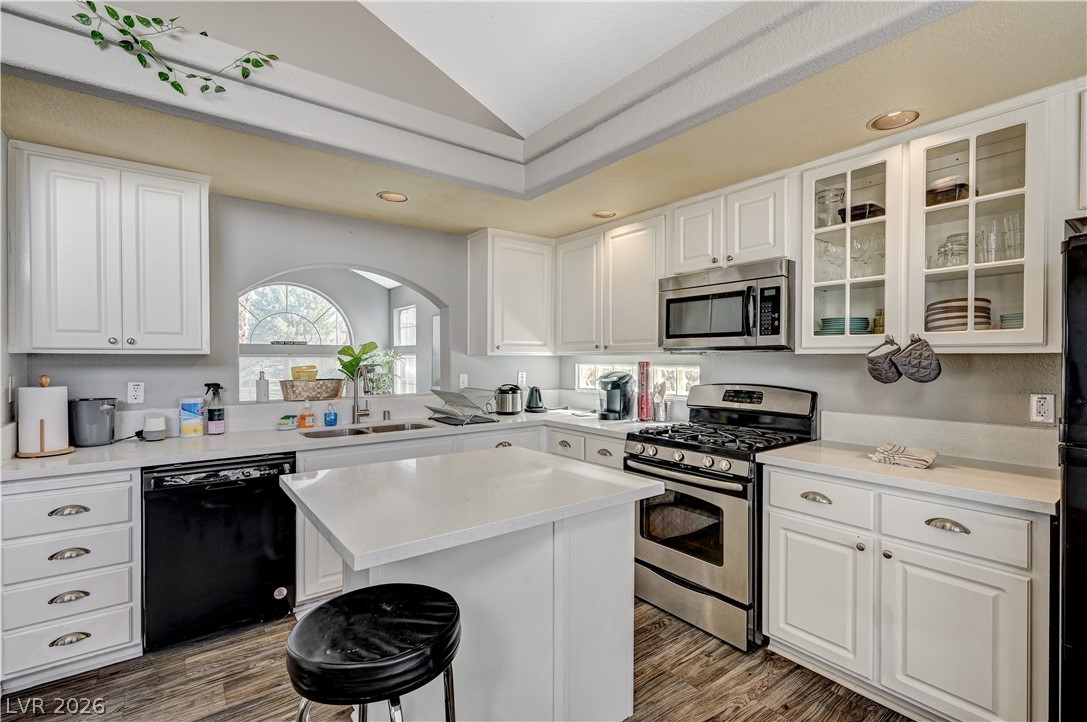 8863 Chapman Point Las Vegas, NV 89129 - Photo 10 of 22 Kitchen with stainless steel appliances, vaulted ceiling, white cabinetry, dark wood-type flooring, and a center island