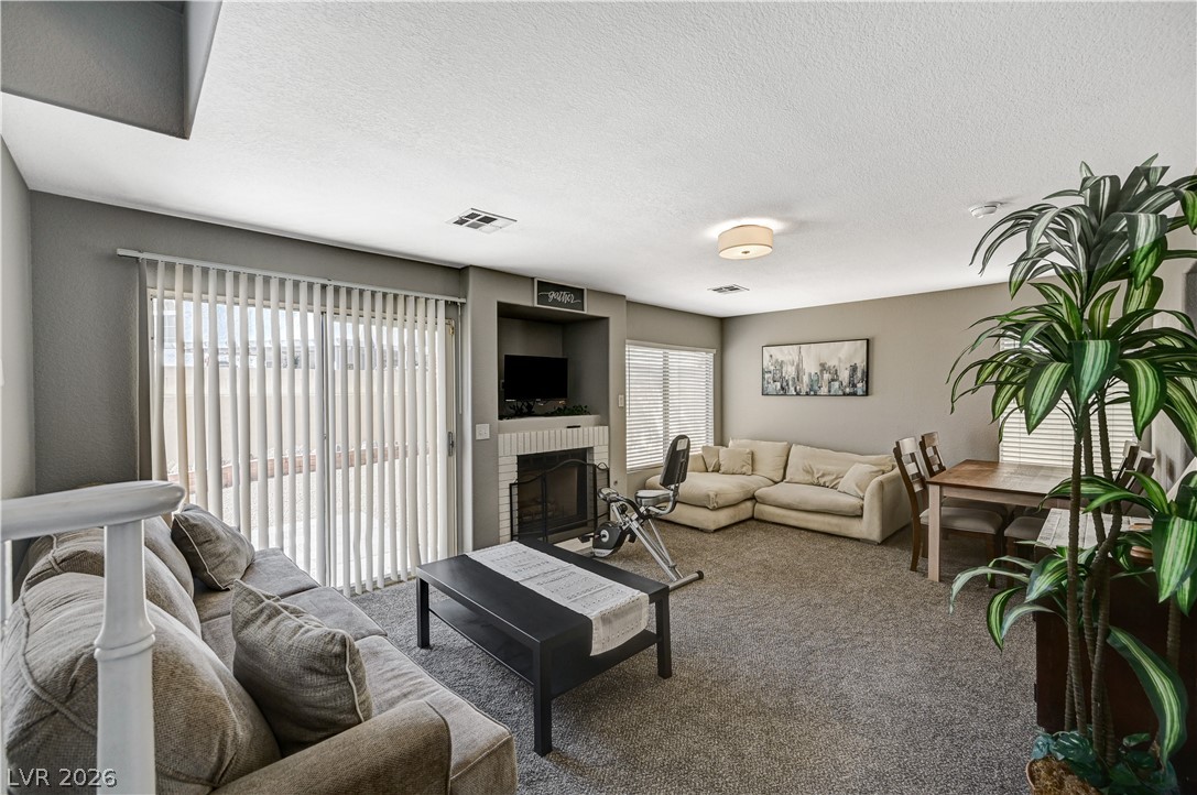 8863 Chapman Point Las Vegas, NV 89129 - Photo 14 of 22 Living room with a brick fireplace, carpet, and a textured ceiling