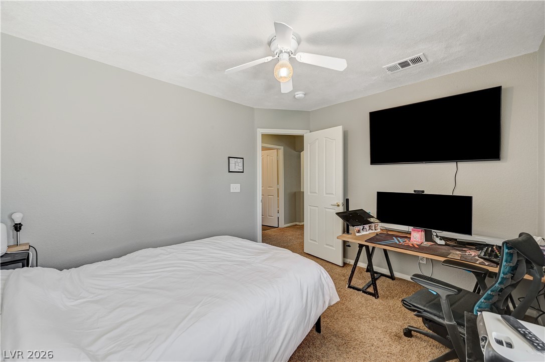 8863 Chapman Point Las Vegas, NV 89129 - Photo 20 of 22 Bedroom featuring light carpet, a ceiling fan, and an office area