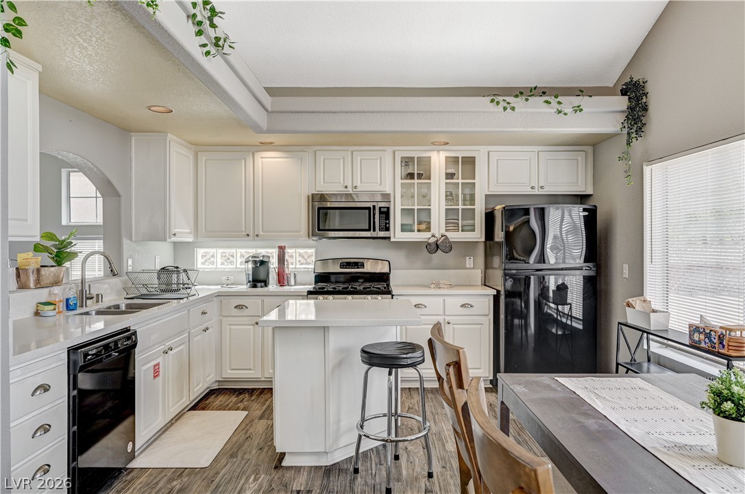8863 Chapman Point Las Vegas, NV 89129 - Photo 8 of 22 Kitchen with black appliances, white cabinetry, glass insert cabinets, a center island, and a kitchen breakfast bar