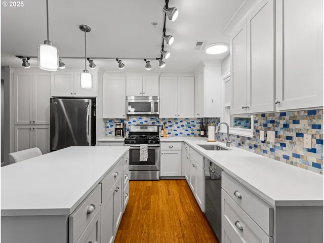 a kitchen with kitchen island a sink a counter space stainless steel appliances and cabinets