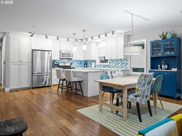 a room with stainless steel appliances kitchen island granite countertop furniture wooden floor and a kitchen view