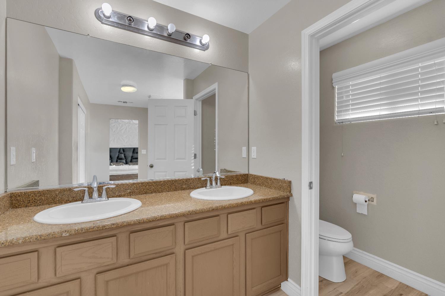 4729 North Rumi Avenue Fresno, CA 93723 - Photo 32 of 35 a bathroom with a granite countertop sink a toilet and a mirror