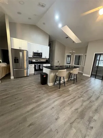 a living room with stainless steel appliances furniture a flat screen tv and view kitchen