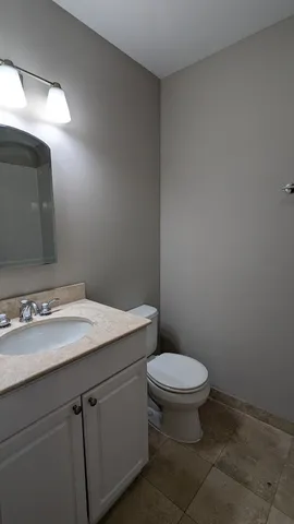 a bathroom with a granite countertop toilet and sink