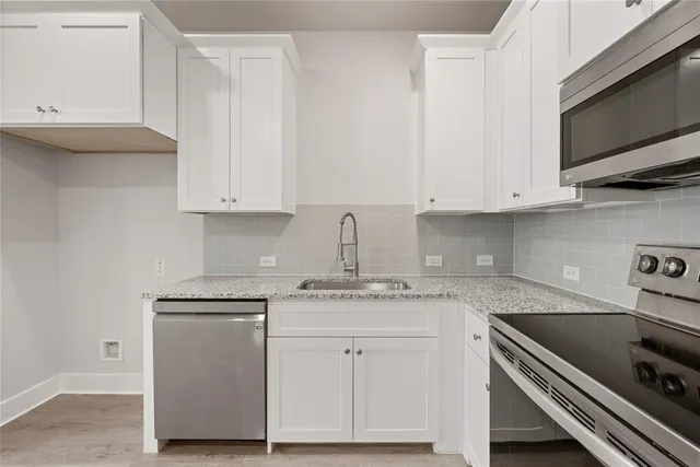 a kitchen with granite countertop white cabinets and a stove