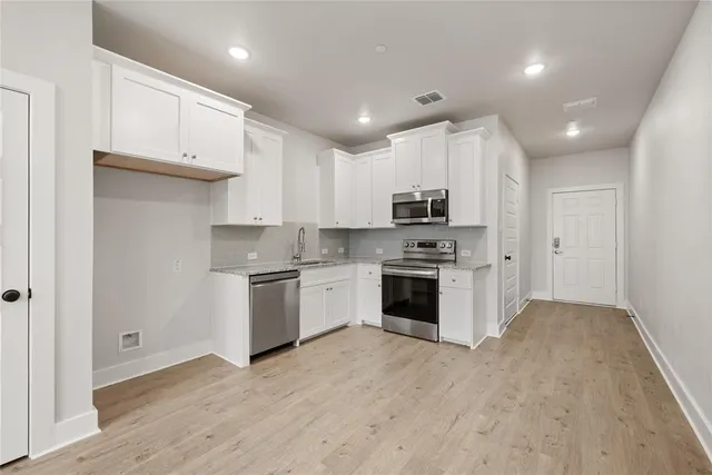 a kitchen with granite countertop white cabinets and stainless steel appliances