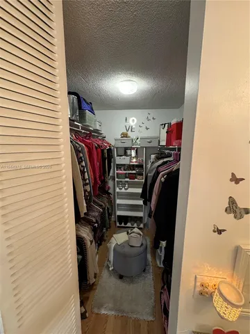 a view of walk in closet with clothes and shoes