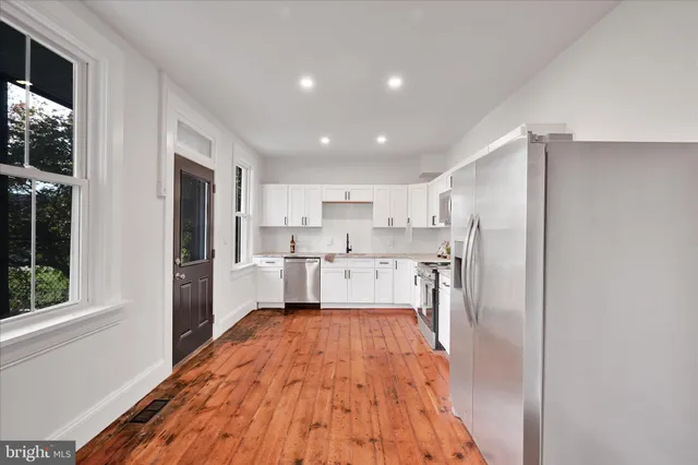 a large kitchen with cabinets wooden floor and stainless steel appliances