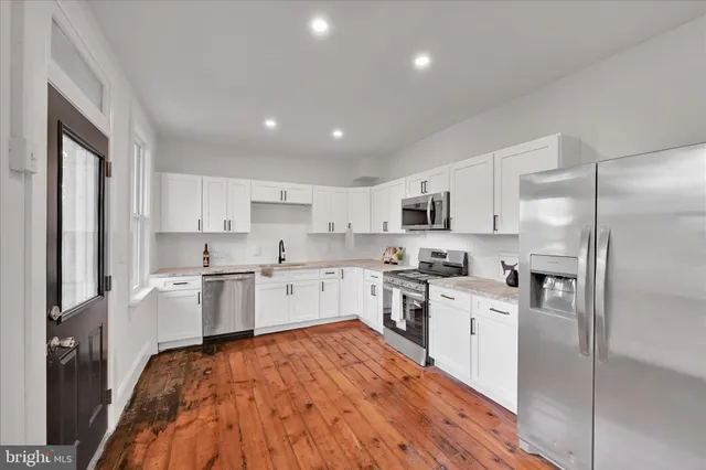 a large kitchen with cabinets wooden floor and stainless steel appliances