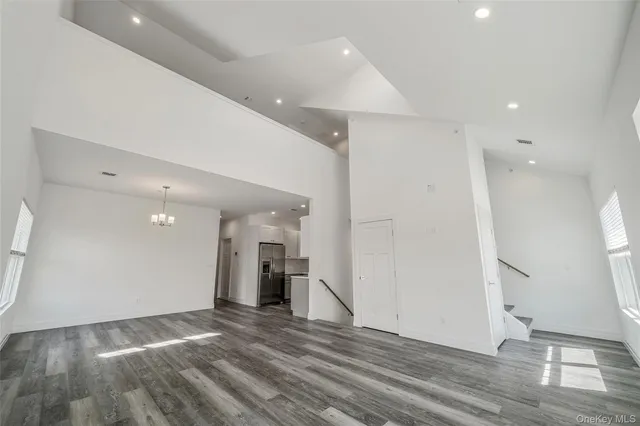a view of a hallway with wooden floor and a refrigerator