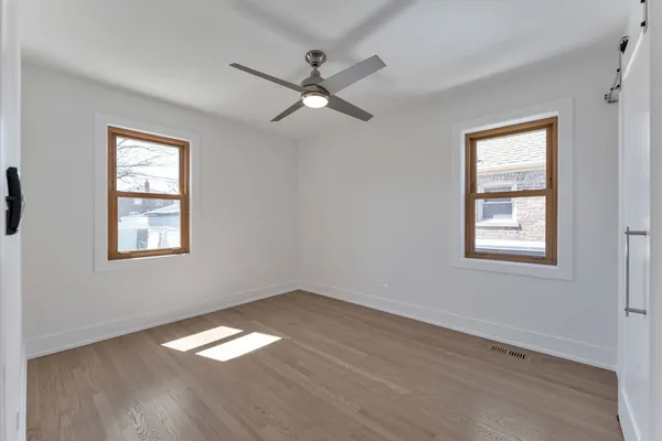 a view of empty room with wooden floor and fan